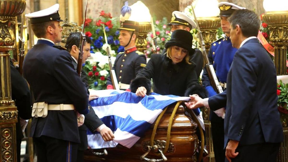 La viuda del expresidente Jorge Batlle, Mercedes Menafra (centro), y el vicepresidente de Uruguay, Raúl Sendic, colocan la bandera nacional sobre el féretro de Batlle, el martes en el Palacio Legislativo en Montevideo.