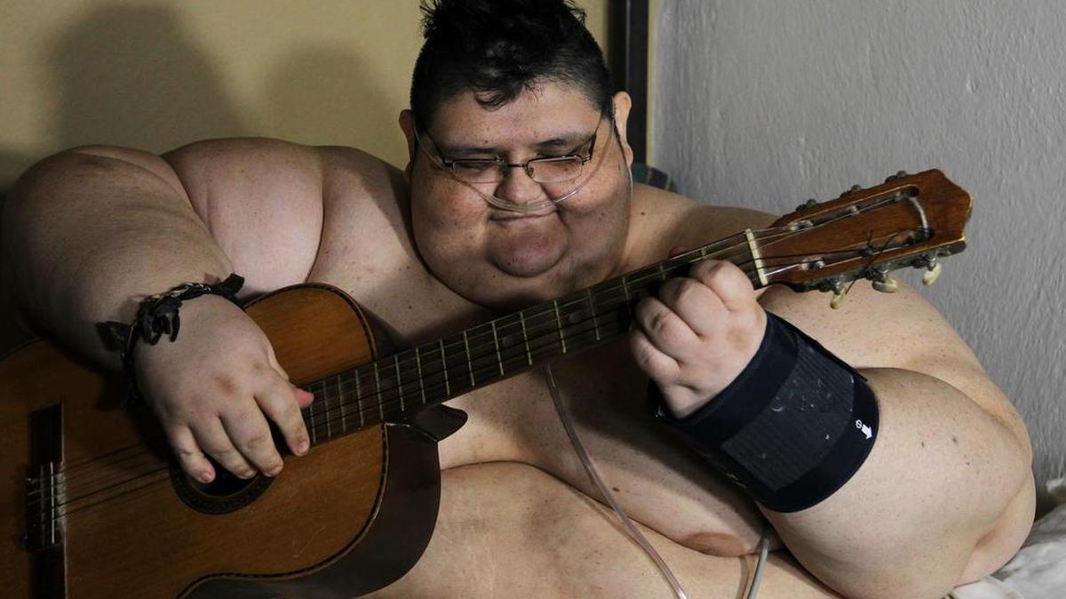 El joven Juan Pedro, un mexicano que con 500 kilos de peso es considerado como el hombre más obeso del mundo, toca la guitarra el miércoles 23 de noviembre de 2016, durante una rueda de prensa en la ciudad de Guadalajara (México).