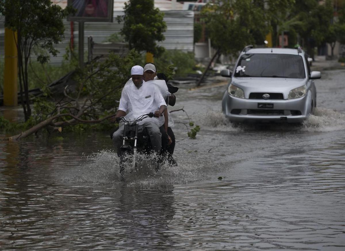 VArias personas transitan en vehículos por una calle inundada horas antes del paso del huracán María el miércoles 20 de septiembre de 2017, en Punta Cana.