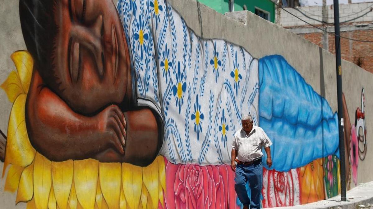 Un hombre camina frente a un mural realizado por el grupo de artistas del Colectivo Tomate, en una calle del barrio de Xanenetla en la ciudad de Puebla, México.