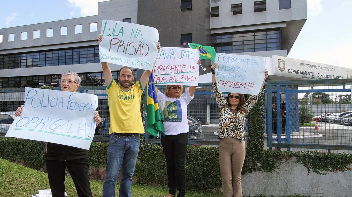 Manifestantes sostienen carteles a favor de la investigación policial contra el caso de corrupción Lava Jato, que implica al expresidente brasileño Luiz Inácio Lula da Silva, mientras se realiza una rueda de prensa, hoy, viernes 4 de marzo de 2016, en la sede de la Policía Federal en la ciudad sureña de Curitiba (Brasil).