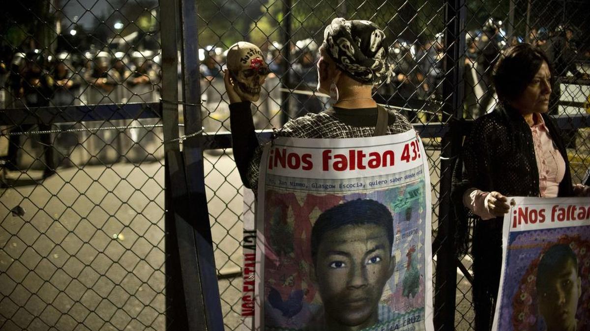 Una manifestante se encuentra junto a una valla de seguridad de policías antidisturbios durante una protesta exigiendo justicia en el caso de los estudiantes de Ayotzinapa, en la Ciudad de México el 26 de noviembre de 2015. Los padres y familiares de las víctimas comenzaron una concentración indefinida fuera de la residencia presidencial Los Pinos para exigir al gobierno la investigación sobre la desaparición de los estudiantes.
