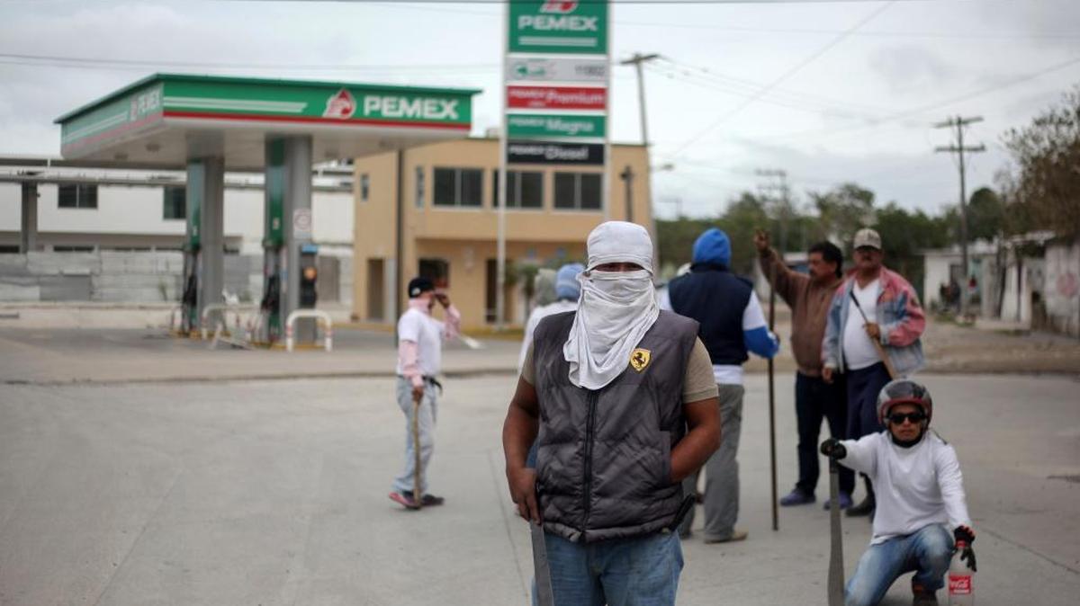 Un hombre enmascarado hace guardia frente a una estación de servicio en Veracruz, México.