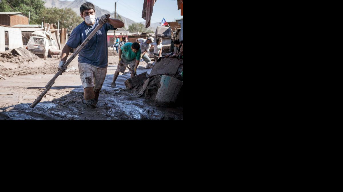 
Personas participan el sábado sen la limpieza de una calle anegada de lodo en la localidad de Paipote, Chile. 
