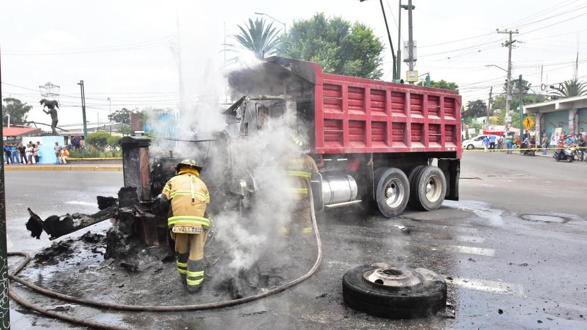 Bomberos intentan sofocar las llamas de un vehículo incendiado en la zona urbana de Tláhuac donde se realizó un operativo el jueves 20 de julio de 2017, en Ciudad de México.