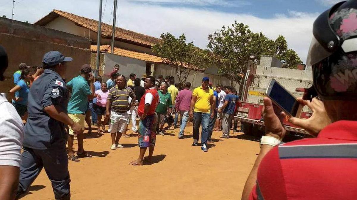 Fotografía cedida por la Policía Militar del estado de Minas Gerais (PMMG), en la que se ve a un grupo de personas reunidas al frente de una guardería en la que murieron cuatro niños el jueves 5 de octubre de 2017, en Janaúba (Brasil).