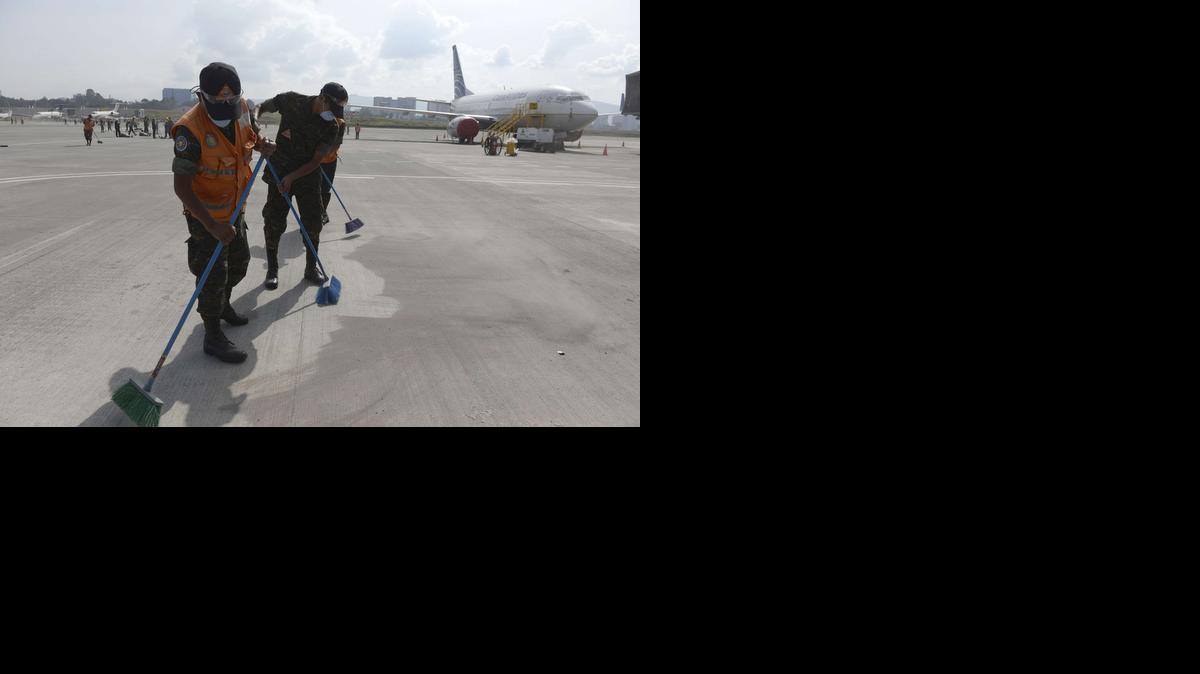 
Miembros del Ejército limpian el domingo las cenizas arrojadas por el Volcán de Fuego en la pista del aeropuerto internacional La Aurora, en Ciudad de Guatemala. Miles de personas estaban varadas en esa terminal aérea.


