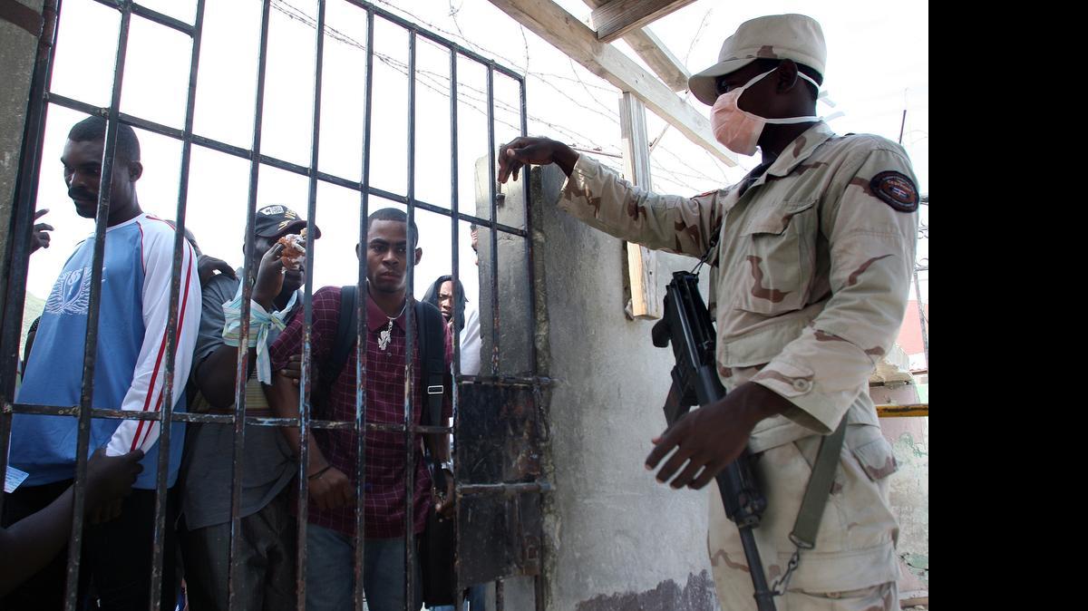 
Un oficial armado de inmigración de República Dominicana, con el rostro cubierto, reliza inspecciones a los haitianos que tratan de cruzar la frontera.en el 2010.

