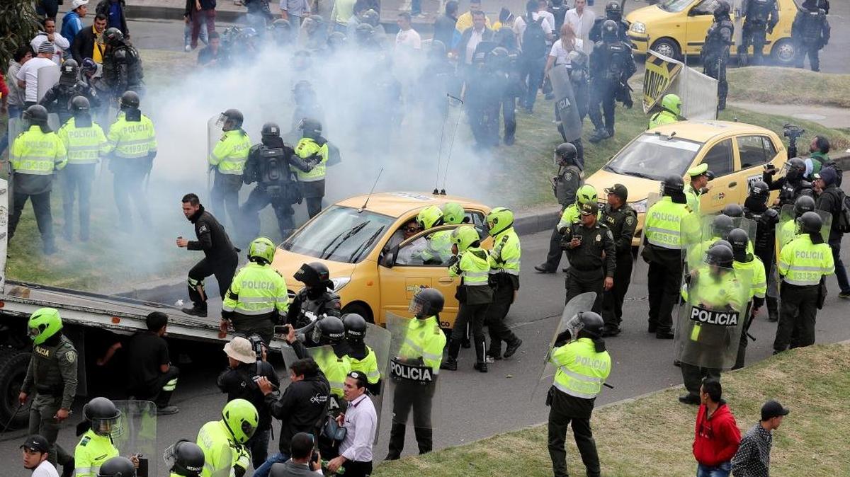 Miembros de la Policía de Colombia inmovilizan taxis durante una protesta el lunes 23 de octubre de 2017, en Bogotá (Colombia). Al menos 600 taxistas de la capital colombiana comenzaron una huelga indefinida para que las autoridades regulen el servicio de transporte que prestan las plataformas Uber y Cabify y que, según denuncian, ha afectado la movilidad en la ciudad y disminuido las ganancias del gremio.