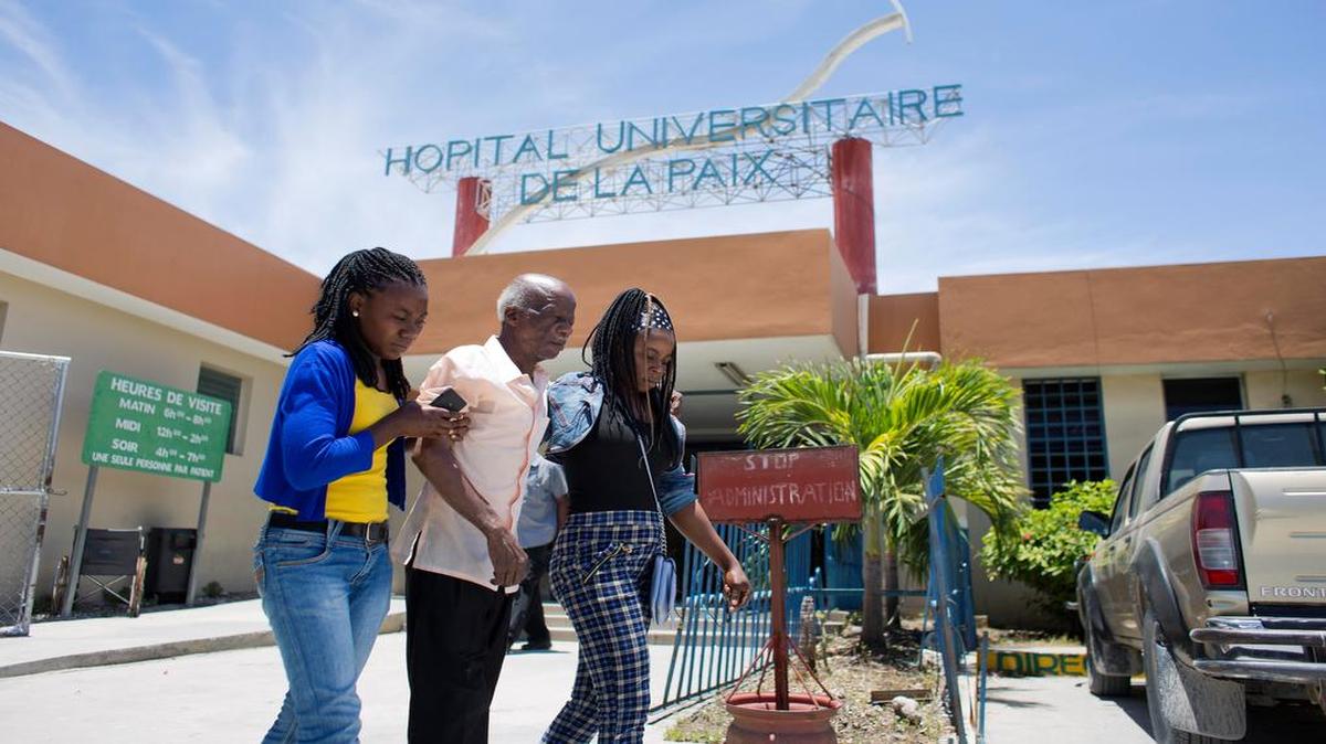 Bien-Aime Edwin de 75 años, es auxiliado por sus nietas al salir del Hospital Universitario La Paix.