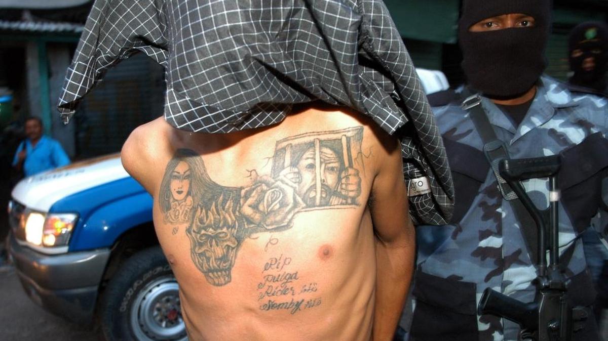 Un miembro de la policía nacional de Honduras custodia a un presunto pandillero de la ‘Mara Salvatrucha’. Un estudio divulgado el lunes determinó que el 28% de los consultados atribuye el desplazamiento de su hogar a las pandillas.