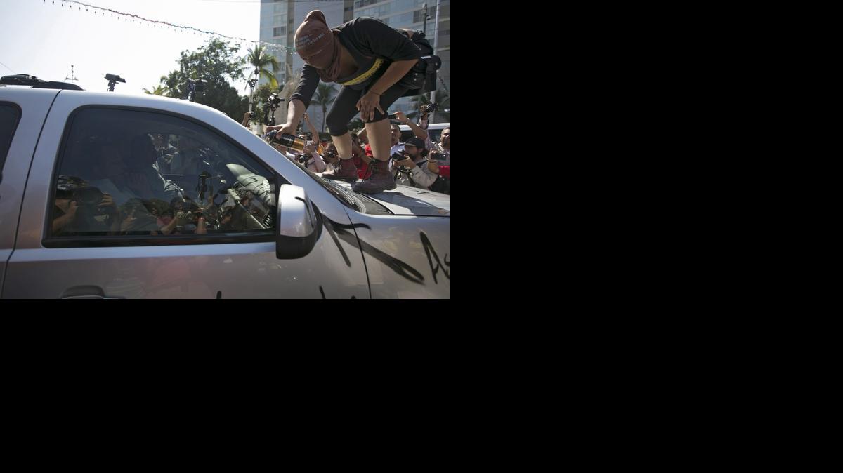 
Una manifestante pinta un grafiti en el auto del alcalde de Acapulco, México. 
