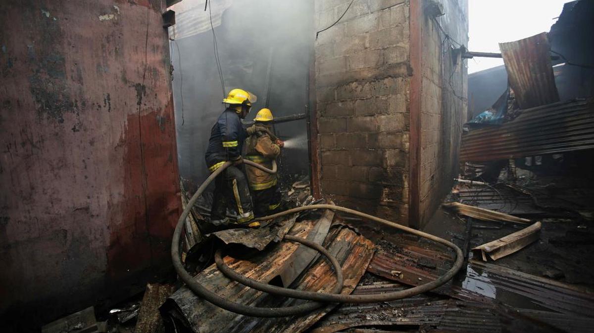 Dos bomberos apagan las llamas de un incendio que destruyó varios establecimientos comerciales el domingo 14 de mayo de 2017, en el Mercado Oriental de Managua (Nicaragua).