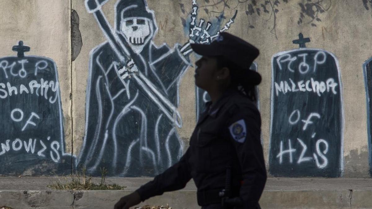 Una policía pasa junto a un muro con imágenes de pandilleros que han muerto en un vecindario controlado por la Mara Salvatrucha en Ilopango, El Salvador, en una imagen de abril del 2014