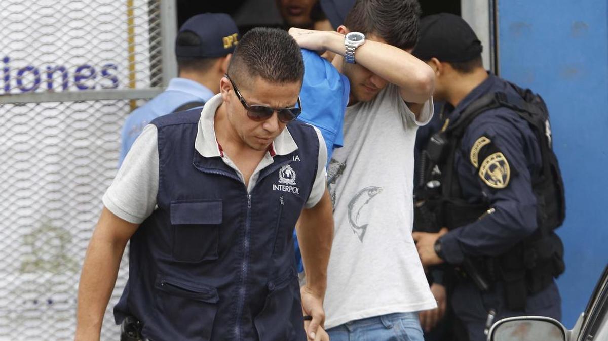Un policía hondureño custodia a uno de los cinco hombres de nacionalidad siria que fue detenido en el aeropuerto internacional de Toncontin (Honduras) con pasaporte griego falso y que pretendía llegar a Estados Unidos.