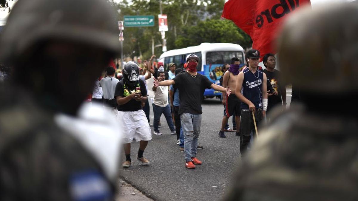 Simpatizantes del candidato opositor Salvador Nasralla participan en una protesta, observada por soldados del ejército, el 6 de diciembre de 2017 en Tegucigalpa.