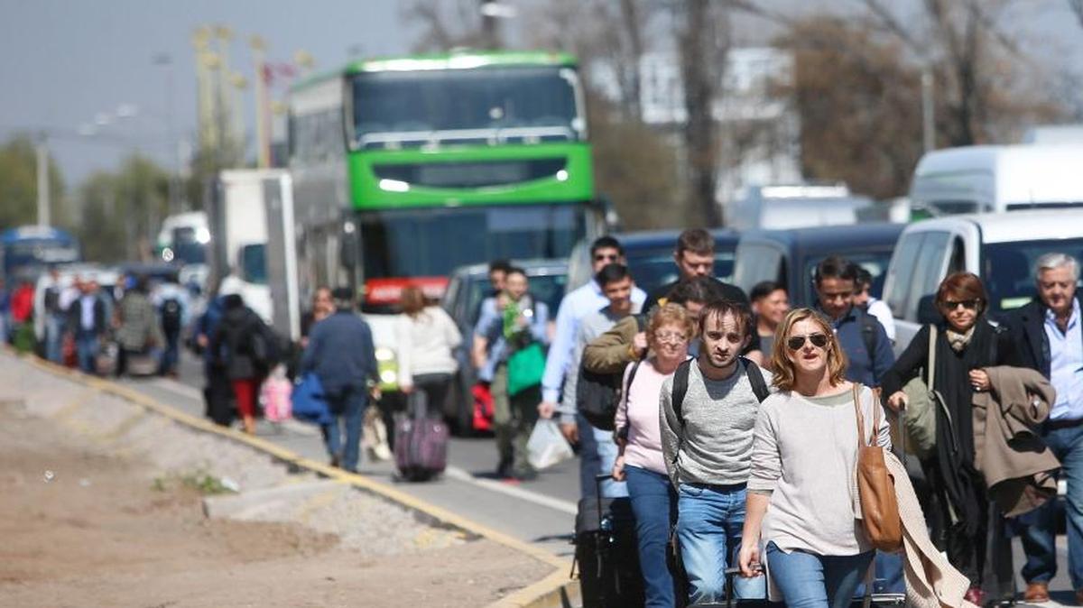 Personas caminan para llegar hasta el aeropuerto debido a una protesta de taxistas que bloquea el acceso y salida del lugar el lunes 4 de septiembre de 2017, en Santiago (Chile). Los taxistas se manifiestan contra la operación en el país de las empresas Uber y Cabify, durante un paro que tiene lugar en varias ciudades de Chile.