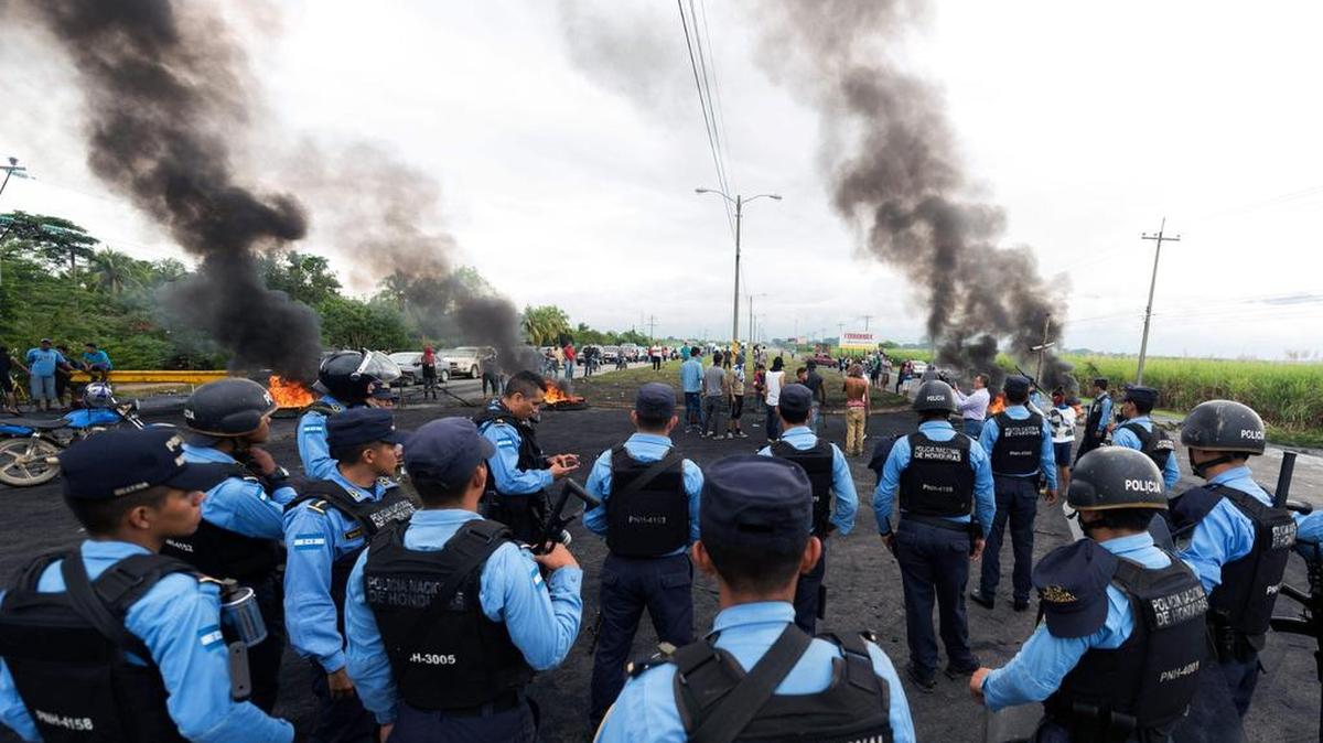 La Policía Nacional hondureña permanece alerta mientras los partidarios del candidato presidencial por la Alianza de Oposición de Honduras contra la dictadura, Salvador Nasralla, prendieron fuego a una barricada para bloquear el paso entre San Pedro Sula y El Progreso, 200 kilómetros al norte de Tegucigalpa, el 4 de diciembre de 2017.