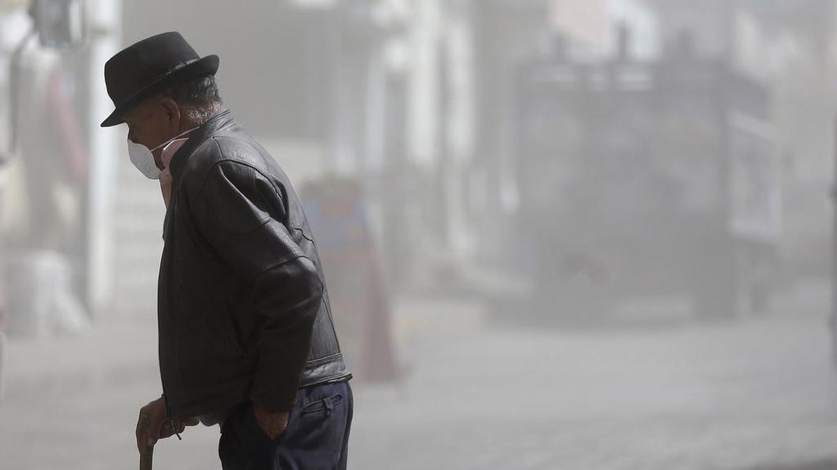 Un hombre lleva una máscara para protegerse de la lluvia constante de ceniza volcánica arrojada por el volcán Tungurahua mientras cruza una calle en Quero, Ecuador, jueves, 19 de noviembre de 2015.