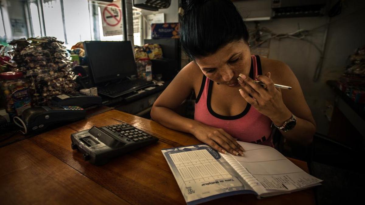 Yessika Carrera anota todo lo que vende en una gasolinera en Caracas, Venezuela, por falta de electricidad para la computadora.