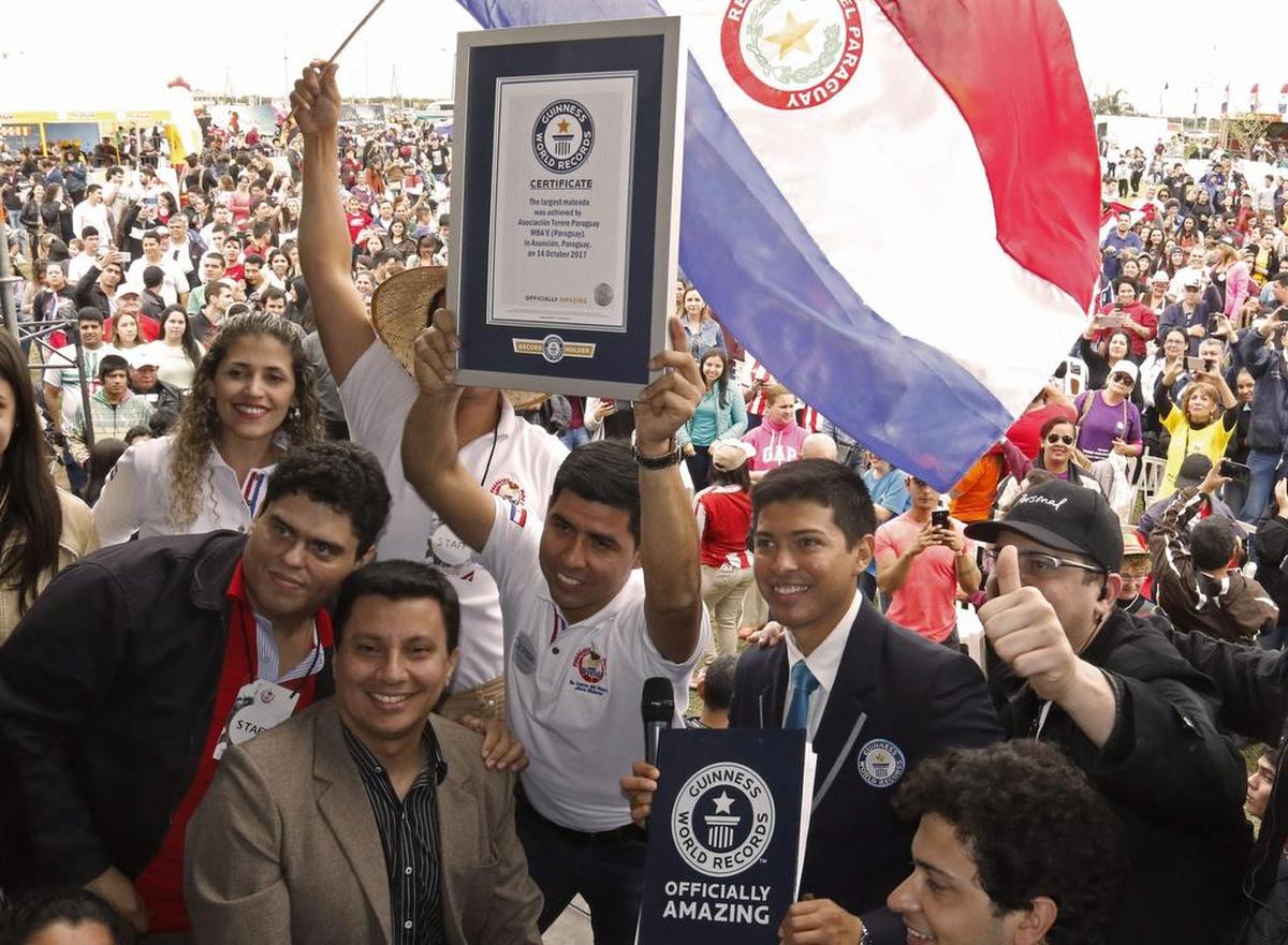 Roberto Servin (centro) presidente de la Asociación de Tereré (infusión paraguaya de yerba mate y agua fría) sostiene el certificado del Récord Mundial de Guinness para la ronda más grande de 'tereré' del mundo, en Asunción, el 14 de octubre de 2017.