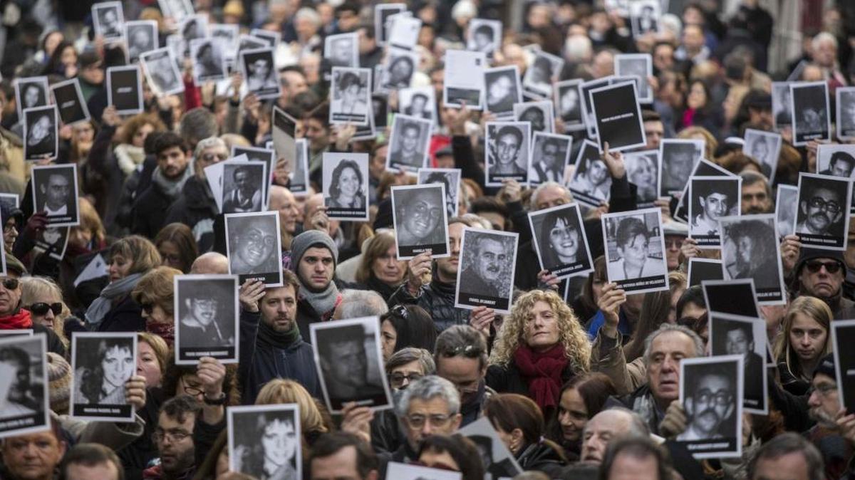 Cientos de personas piden justicia mientras sostienen fotos de las 85 víctimas del ataque terrorista contra la AMIA.