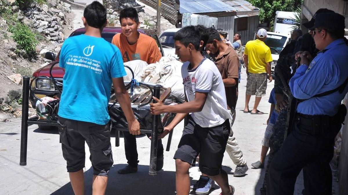 Jóvenes cargan una cama este jueves en un barrio de Tegucigalpa, Honduras, del que han huido varias familias por amenazas de muerte de las pandillas