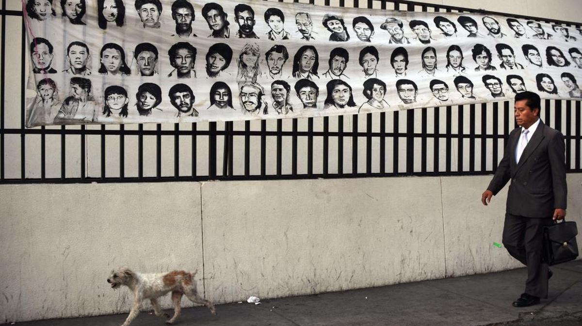 Un hombre camina el lunes por una calle donde se muestran fotos de personas desaparecidas durante el conflicto armado de Guatemala. AI repudió la suspensión del juicio contra el ex dictador José Efraín Ríos Montt.
