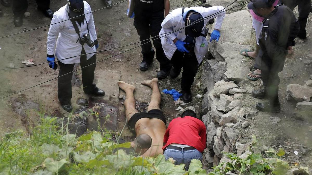 Investigadores en la escena de crimen analizan uno de los cuerpos encontrados sin vida en a capital hondureña.