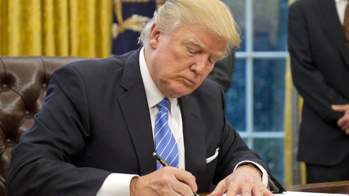 El presidente estadounidense, Donald Trump (c), firma la orden ejecutiva para sacar a EE.UU. del acuerdo comercial TPP (Acuerdo de Asociación Transpacífico), en el Despacho Oval de la Casa Blanca, en Washington, Estados Unidos, el 23 de enero de 2017.