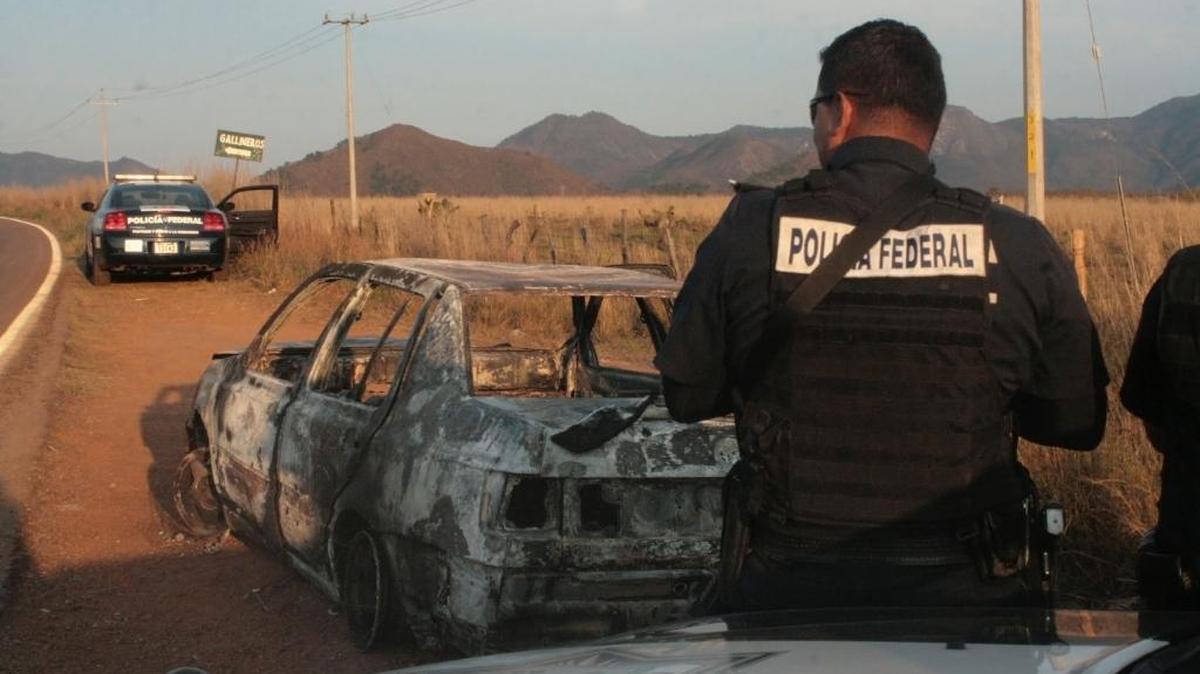 La policía federal vigila un carro baleado y quemado por una pandilla, en abril, cerca de Puerto Vallarta.