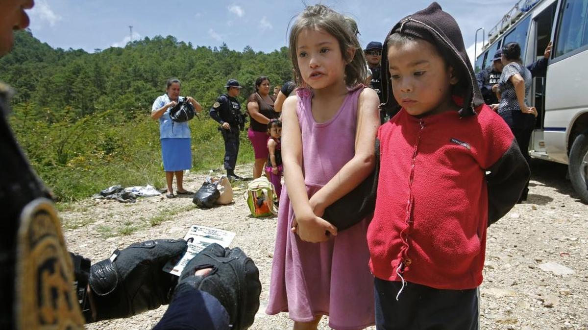 
Una niña con su hermanito responde preguntas sobre su nombre y sus padres, en Ocotepeque, Honduras, en el 2014. Miguel Martínez Madrid (izq.) dirige una unidad especial que determina si niños son llevados de contrabando a EEUU.
