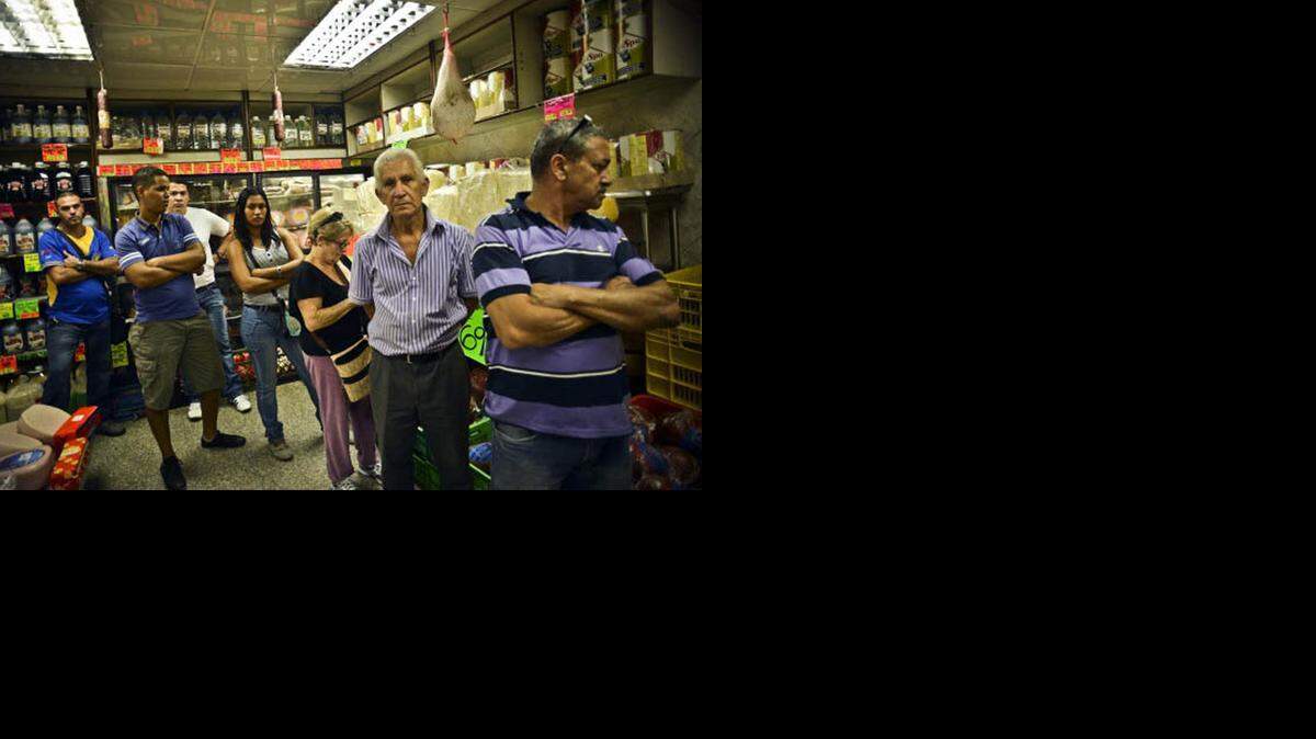 
Clientes esperan en una fila para comprar alimentos en un pequeño mercado en la zona central de Caracas.


