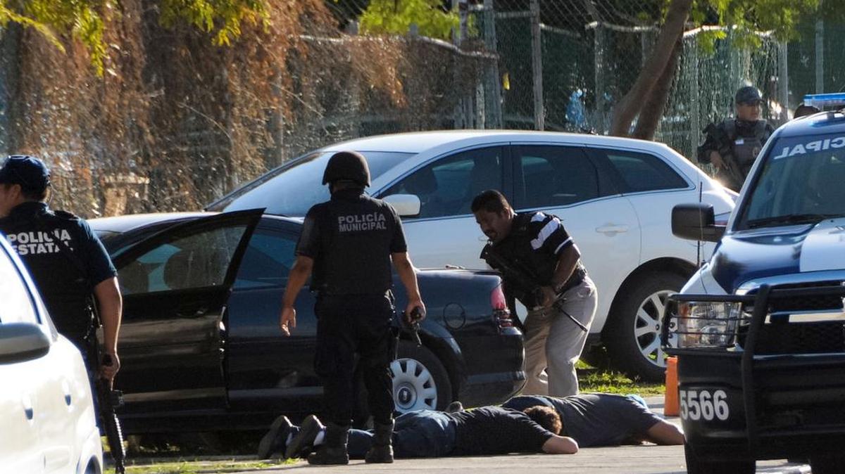 Los policías detienen a sospechosos de un tiroteo luego de otro tiroteo contra el edificio de la Fiscalía del Estado de Quintana Roo, en Cancún, México, el 17 de enero de 2017.