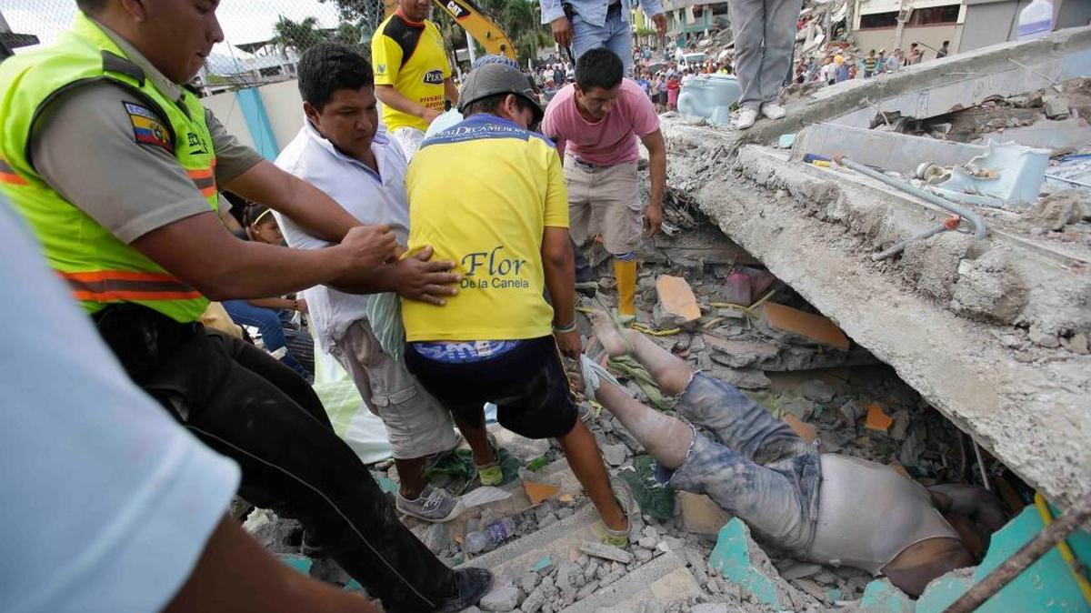 Voluntarios ayudan el domingo a recuperar un cuerpo de los escombros de una casa, destruida por el potente terremoto de 7.8 grados que remeció a Ecuador, causando más de 250 muertos y graves daños a la infraestructura.