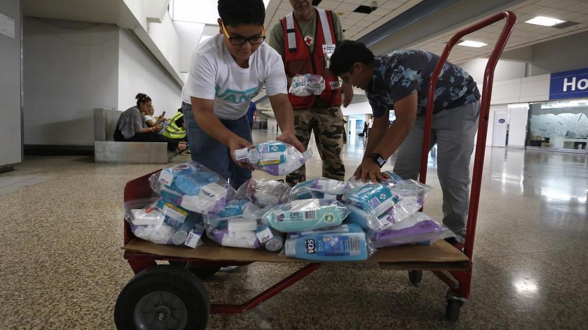 Los hermanos Izal (i) y Zael Guerra (d), traen productos de primera necesidad para ayudar a ciudadanos y turistas de las islas de San Martín y San Thomas que llegan el domingo 10 de septiembre de 2017, al aeropuerto Internacional Luis Muñoz Marín, tras los estragos que causó el huracán Irma en San Juan, Puerto Rico.