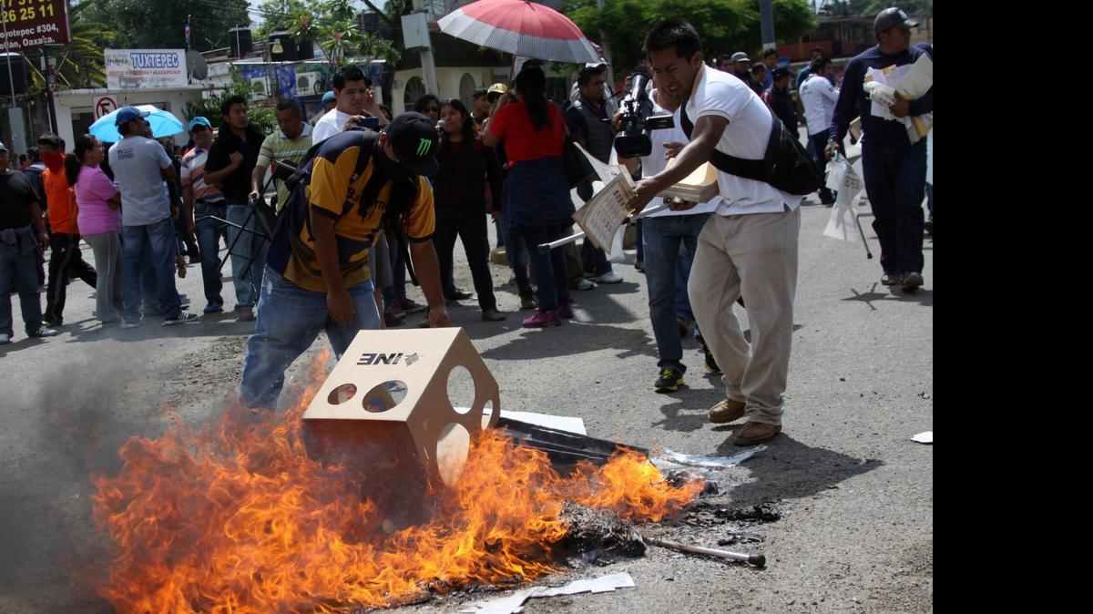 
Profesores del Sindicato Nacional de Trabajadores de la Educación queman el domingo material electoral, durante los comicios legislativos en Oaxaca, México.
