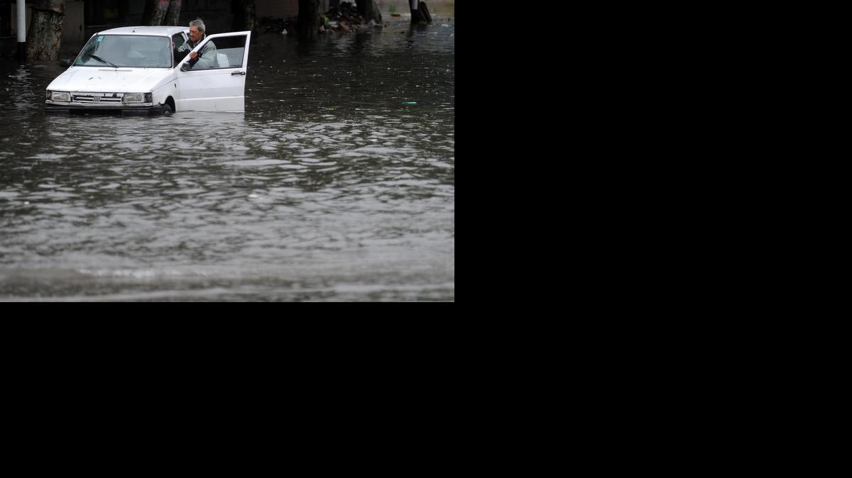 
Un hombre empuja un vehículo en una calle inundada el lunes en Valentín Alsina, en la periferia sur de Buenos Aires, Argentina. 
