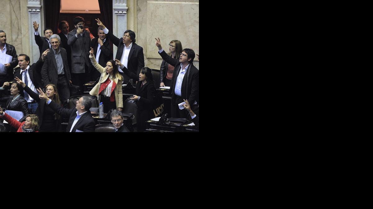
Diputados oficialistas celebran en Buenos Aires la aprobación el jueves de una ley que permite el pago en Argentina de la deuda reestructurada.


