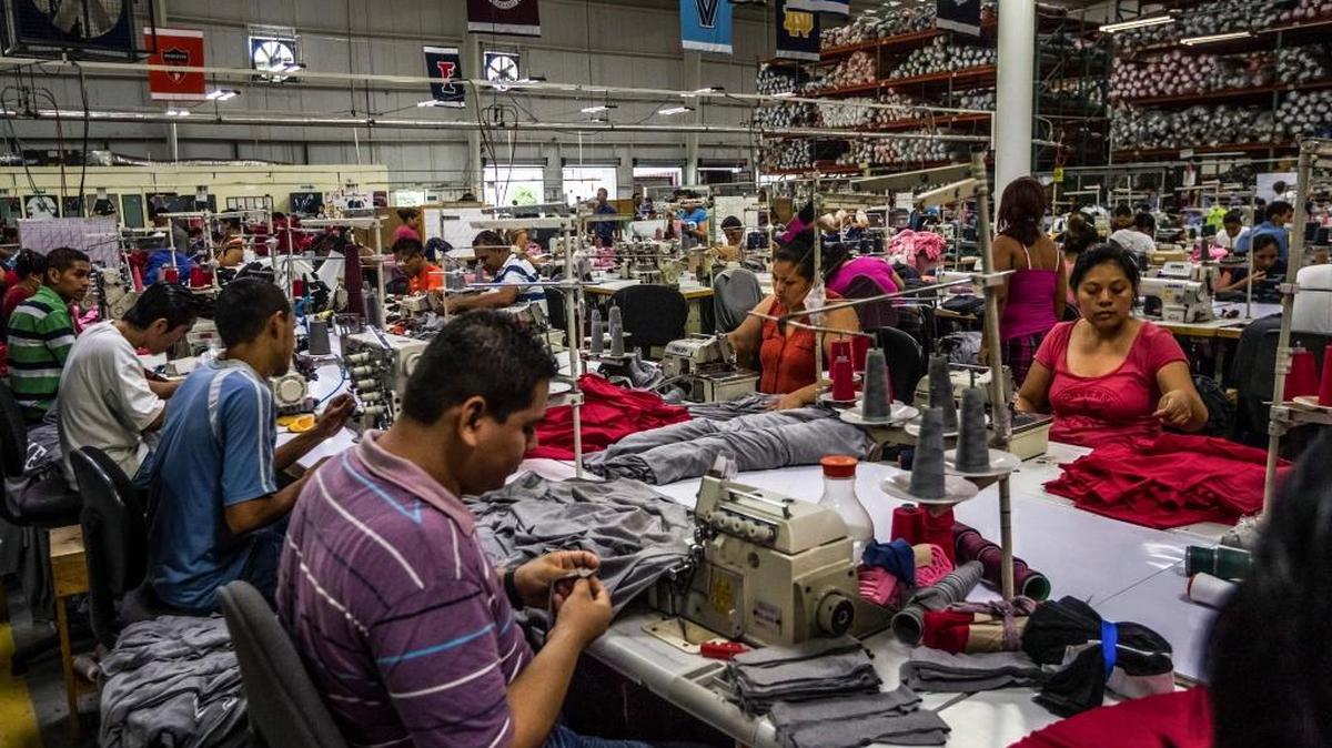 
Trabajadores de una planta de confecciones en El Salvador que cumple pedidos para una empresa norteamericana cosen ‘t-shirts’ con logos universitarios.
