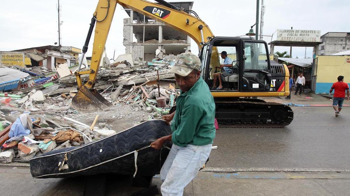 Habitantes de Pedernales (Ecuador), afectado por el terremoto de 7.8 grados en la escala de Richter registrado el sábado en la costa norte de Ecuador, retiran objetos el 17 de abril de 2016, entre las casas destruidas y los escombros.