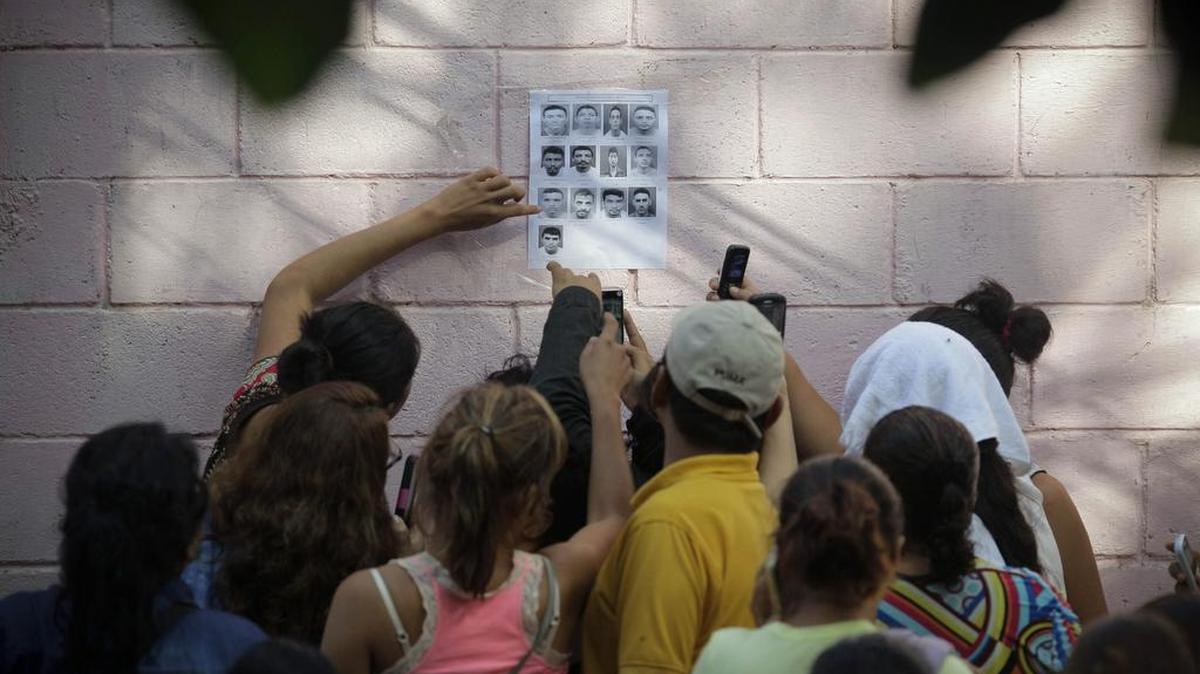 
Familiares observan el domingo una lista de fallecidos producto de una disputa entre miembros de la pandilla Barrio 18 en el penal de Quezaltepeque, El Salvador. 
