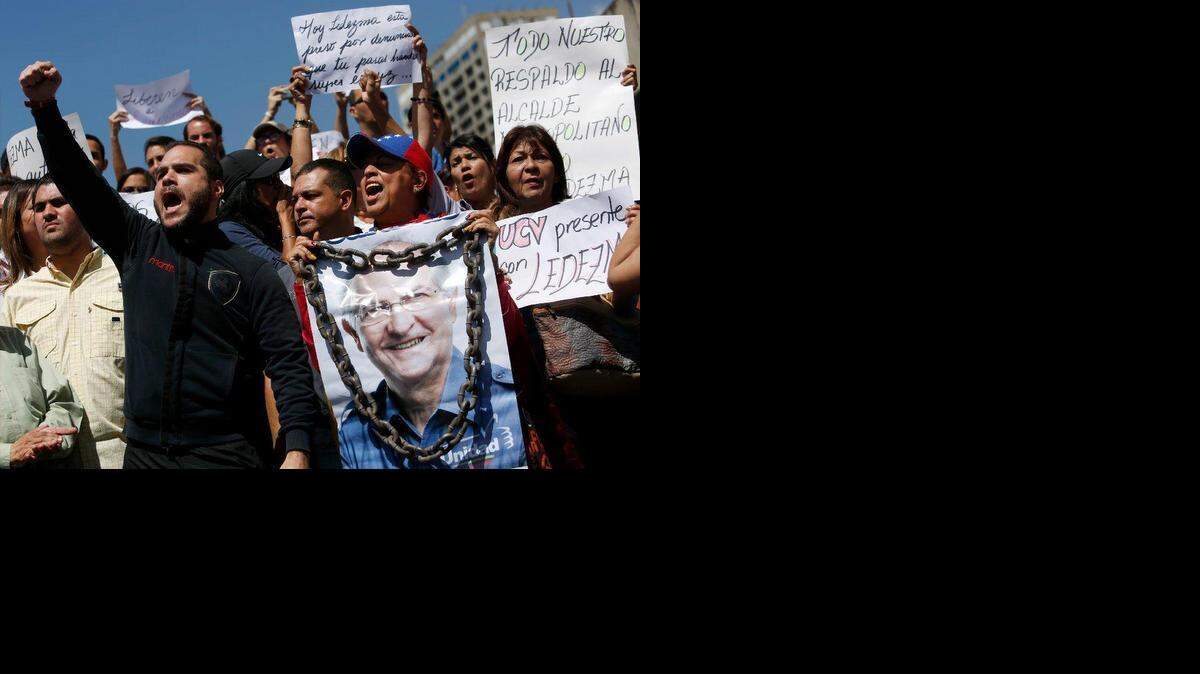 Un partidario del alcalde de Caracas, Antonio Ledezma, sostiene un cartel de él con cadenas durante una protesta para exigir su liberación, en Caracas, Venezuela, el viernes, 20 de febrero de 2015. Los manifestantes están condenando el arresto sorpresa de Ledezma por supuesta conspiración para derrocar al gobierno de el presidente Nicolás Maduro. La noche del jueves Maduro dijo que Ledezma, uno de los líderes de la oposición más vocales, sería castigado por intentar sembrar disturbios en Venezuela.