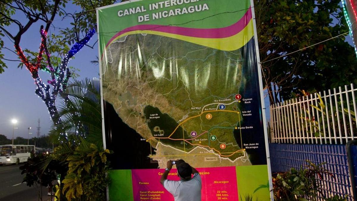 
Un trabajador de la construcción retirado toma fotos de un aviso en Managua que muestra las posibles rutas del canal interoceánico de Nicaragua. Foto archivo.
