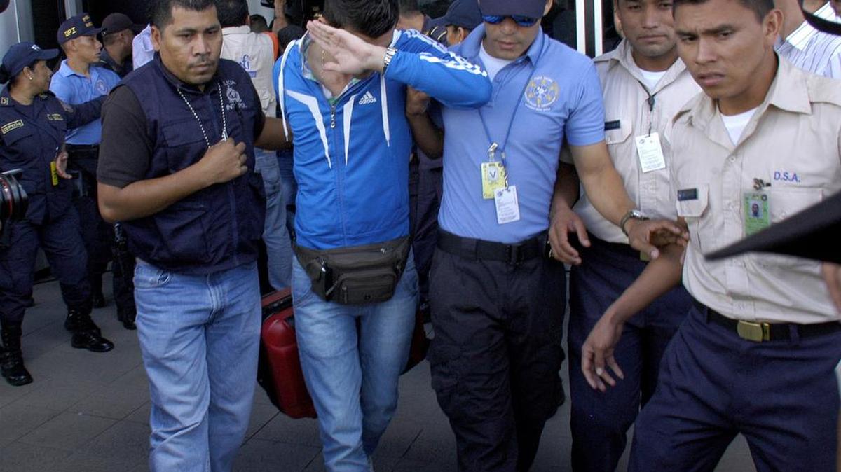 Agentes de la Policía Nacional y de inmigración en Honduras escoltan, el martes 17 de noviembre, a uno de los cinco ciudadanos sirios que fueron interceptados en el aeropuerto de Tegucigalpa cuando intentaban viajar a EEUU con pasaportes falsos.