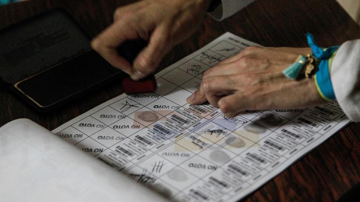 Un miembro de mesa marca con un sello a los electores que se abstuvieron en el cuaderno de votantes el domingo 15 de octubre de 2017, en Caracas (Venezuela).