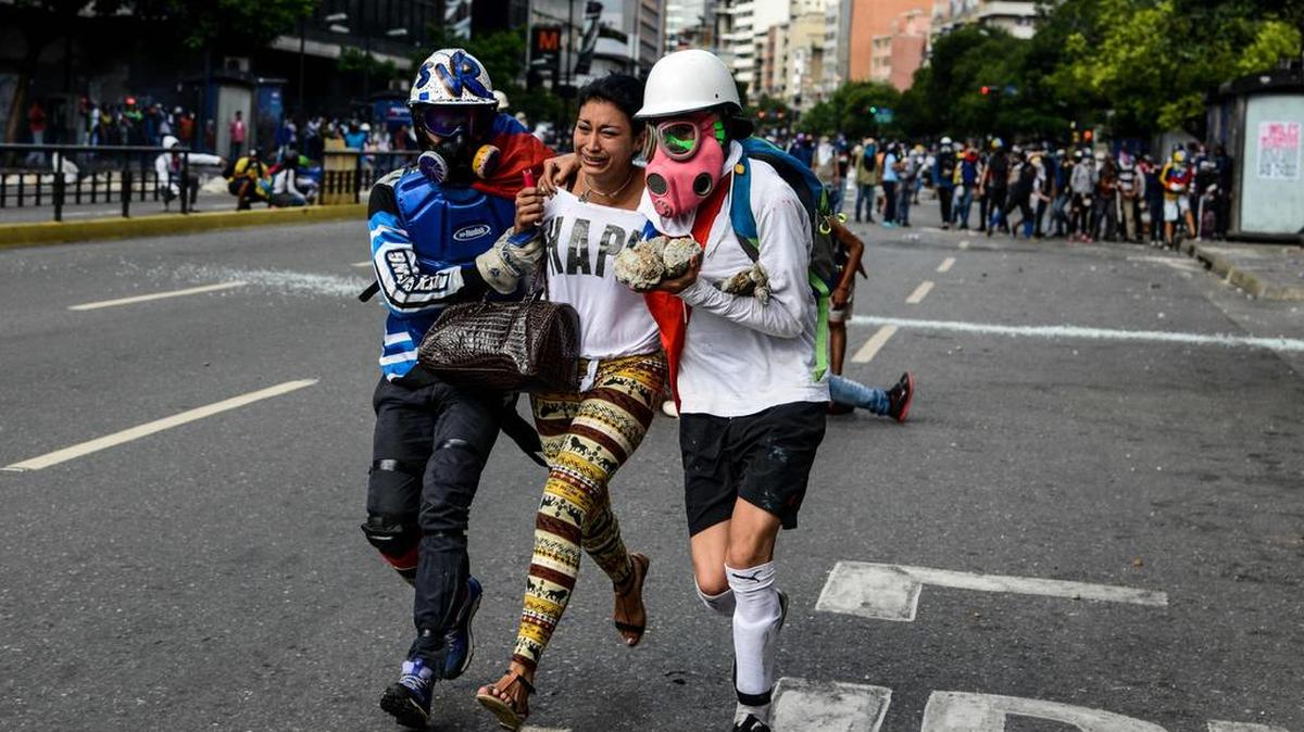 Una mujer recibe ayuda por parte de dos manifestantes el martes en Caracas, durante las protestas contra el régimen de Nicolás Maduro.