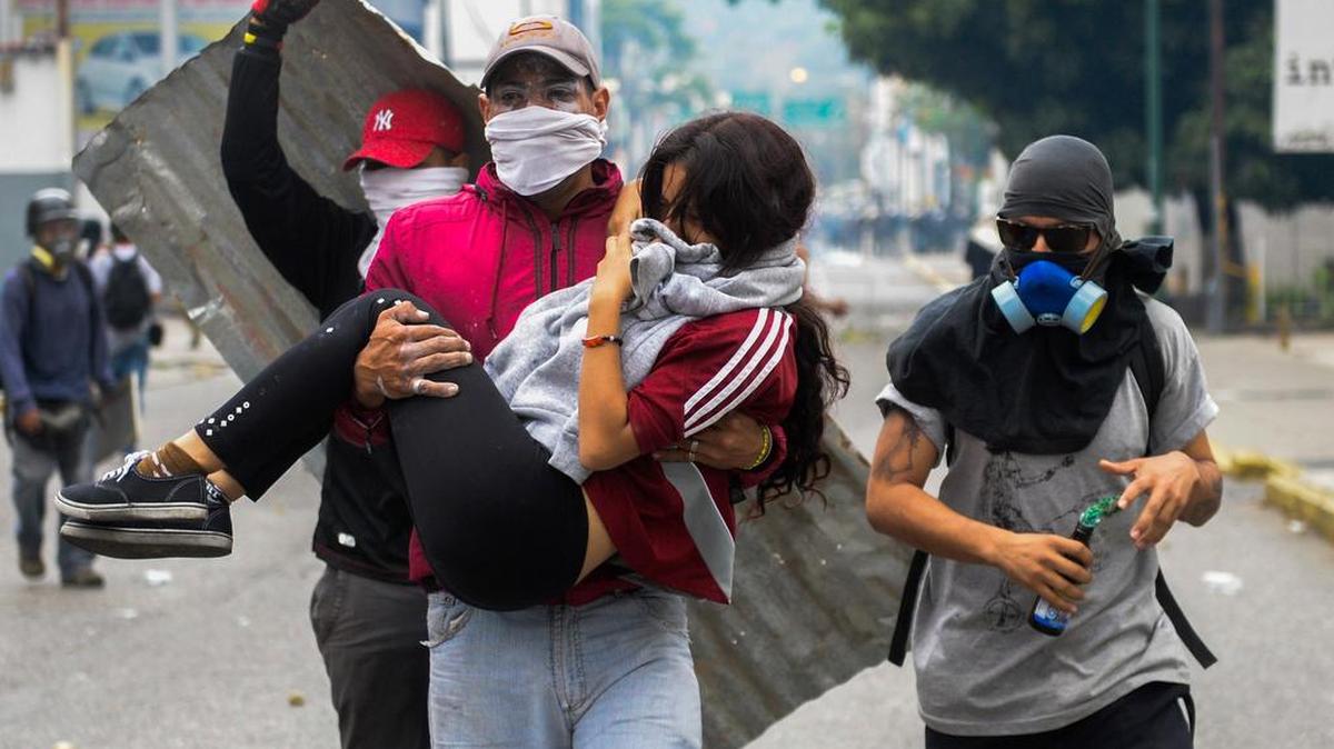 Una joven que fue alcanzada por el gas lacrimógeno disparado por la policía antidisturbios es llevada por otros manifestantes en Caracas el 10 de abril de 2017.