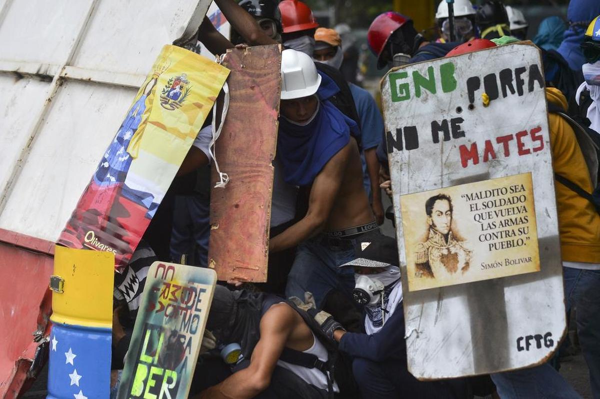Activistas de la oposición se resguardan bajo escudos durante enfrentamientos con la policía antidisturbios en Caracas, Venezuela, el 7 de junio de 2017.