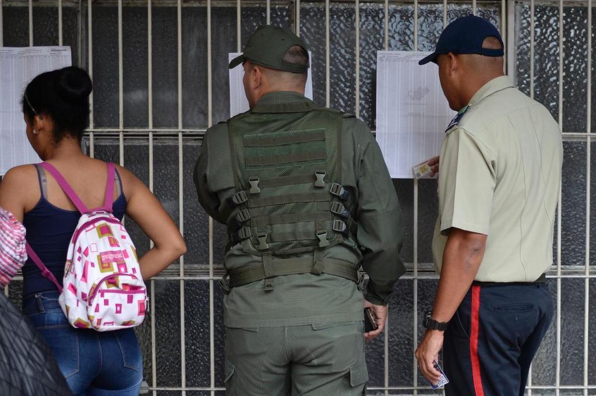 Personas revisan su nombre antes de emitir su voto para elegir una Asamblea Constituyente en Caracas el 30 de julio de 2017.